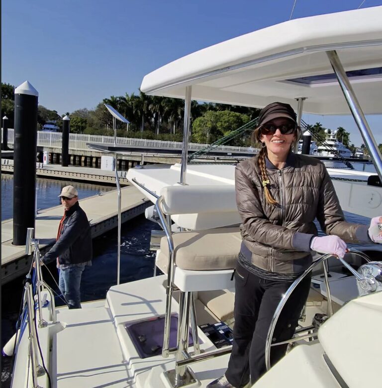 Owner smiling at the helm of a catamaran tied up at a South Florida marina