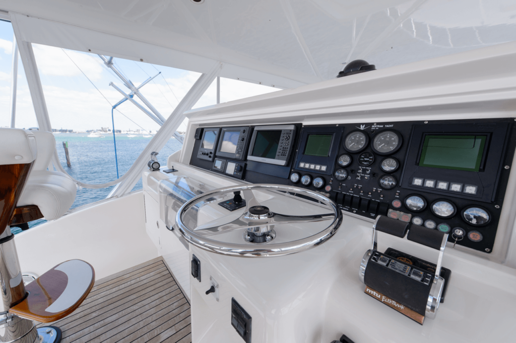 Flybridge helm of a Bertram motor yacht at the marina: wheel, throttles, and electronics