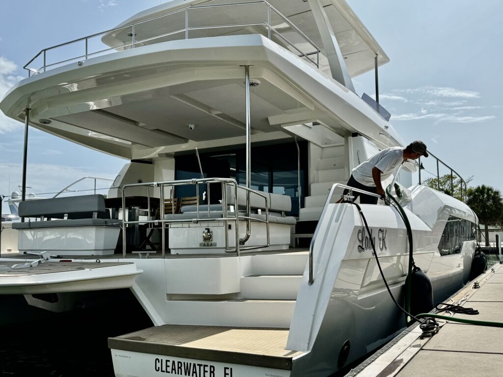 Power cat Lady K at dock, Clearwater FL — crew on side deck with hose (dockside/real boat).