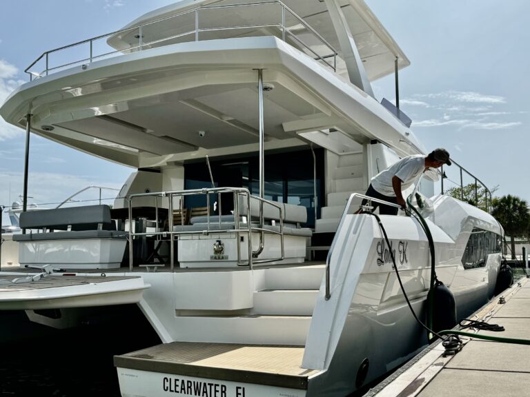 Power cat Lady K at dock, Clearwater FL — crew on side deck with hose (dockside/real boat).